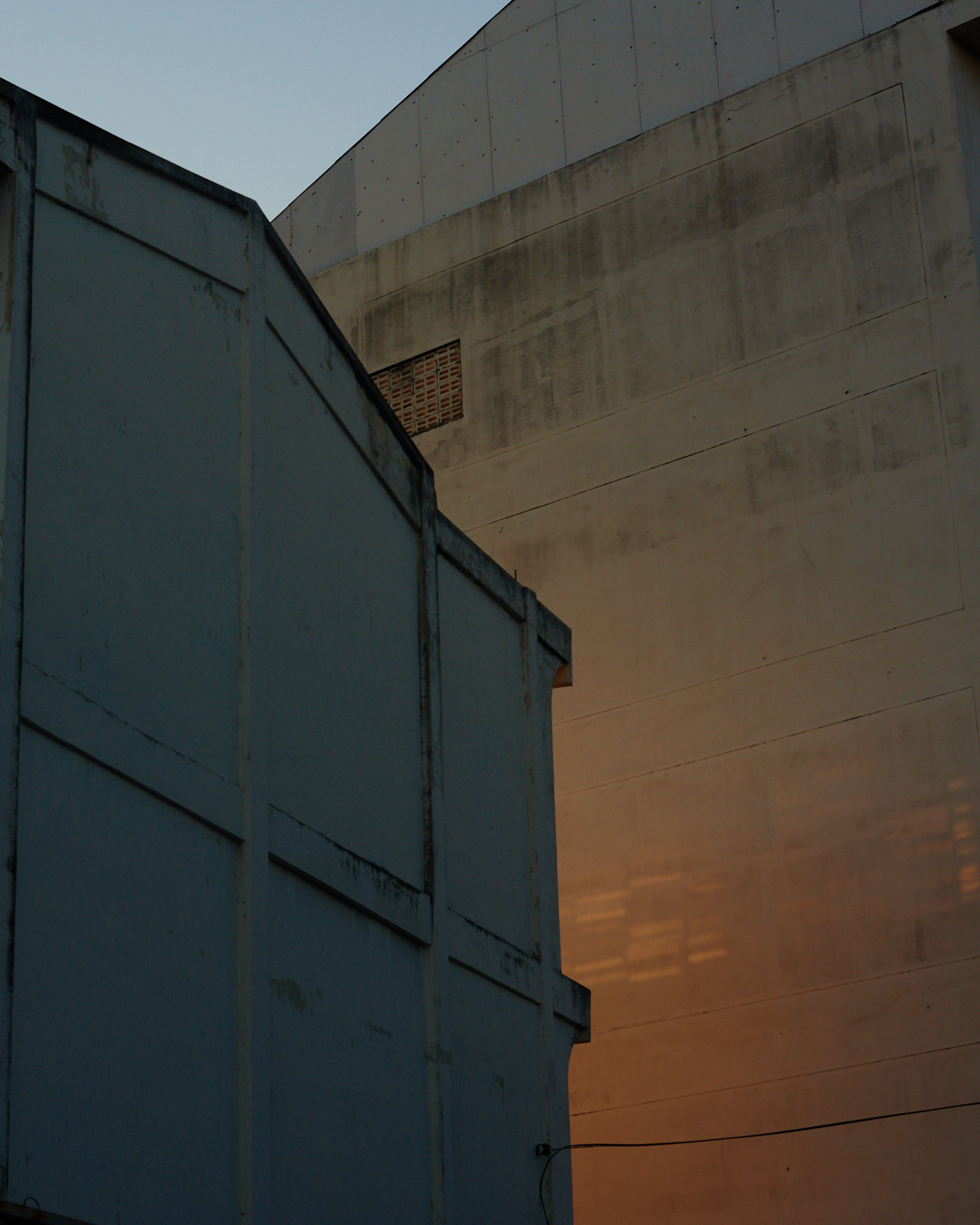 A blue metal structure against a concrete wall at dusk