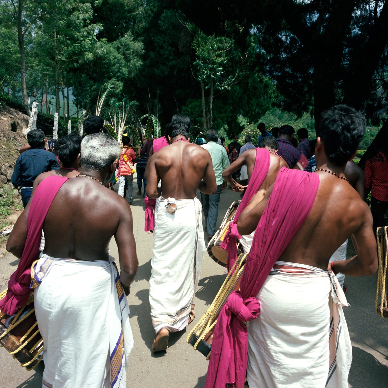Men in white and pink garments walking in procession, seen from behind