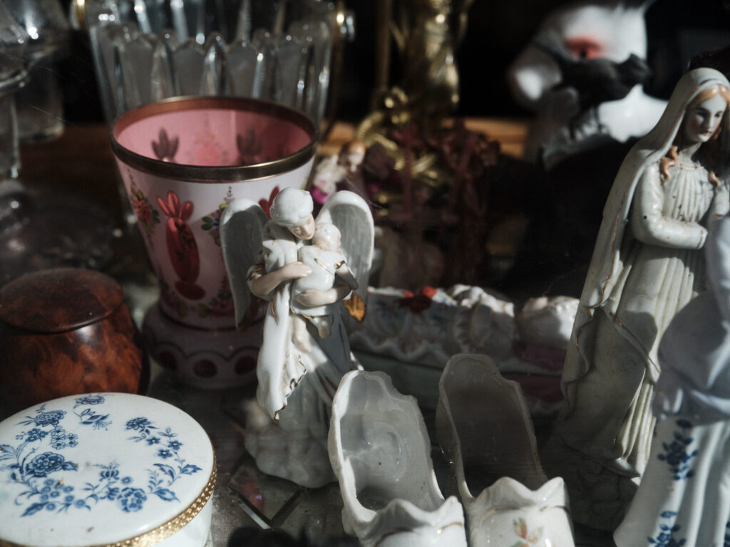 Porcelain figurines and cut glass crowded on a shelf