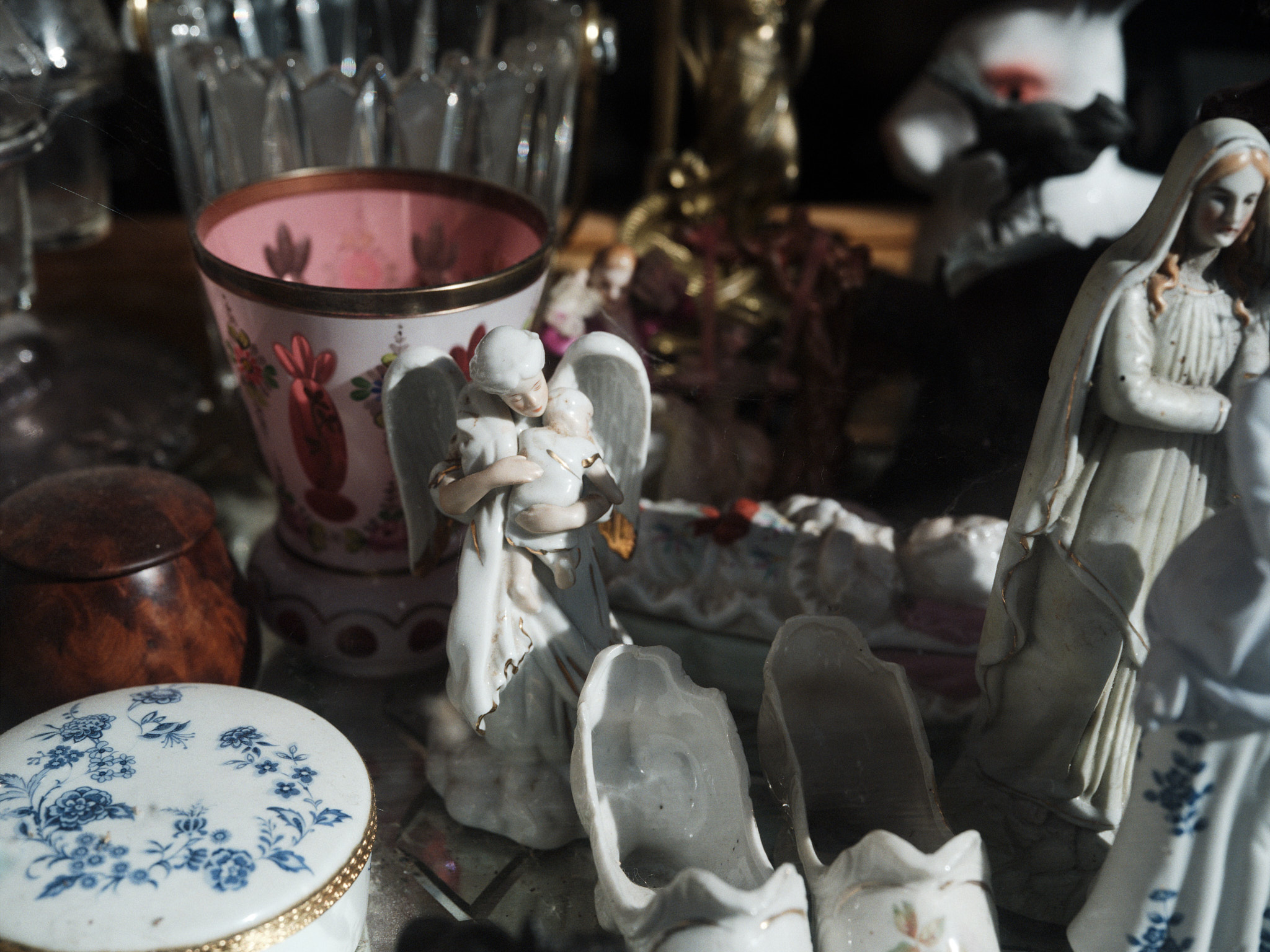 Porcelain figurines and cut glass crowded on a shelf
