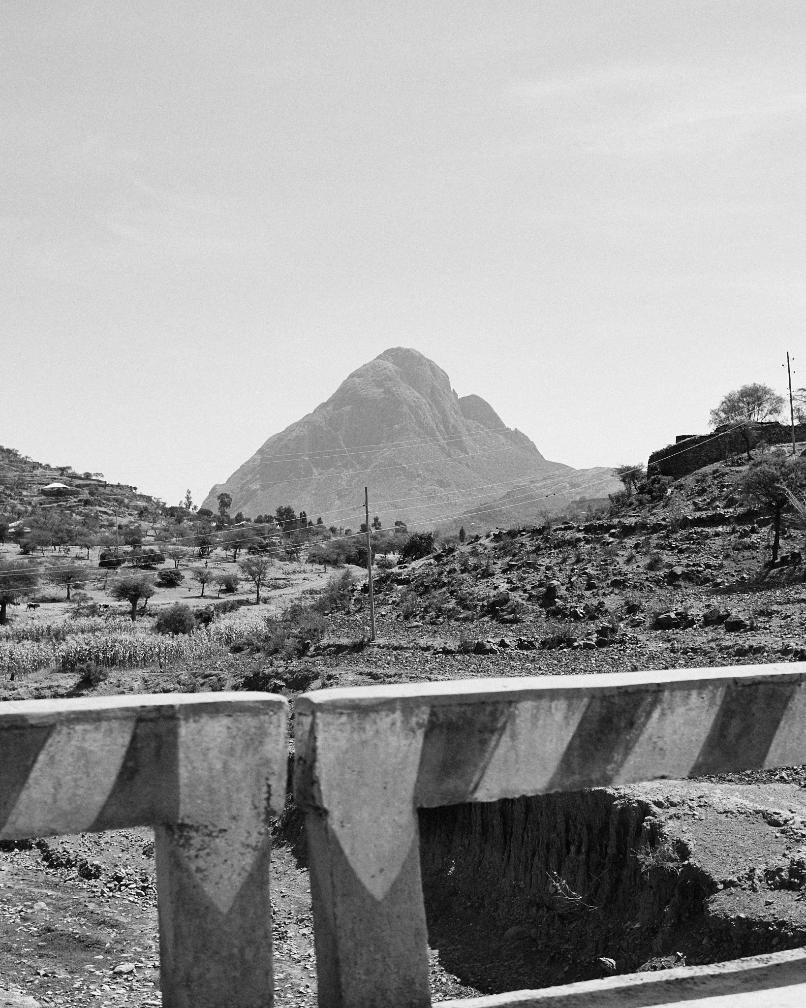 A steep pointed peak rising beyond a low wall hung with cloth