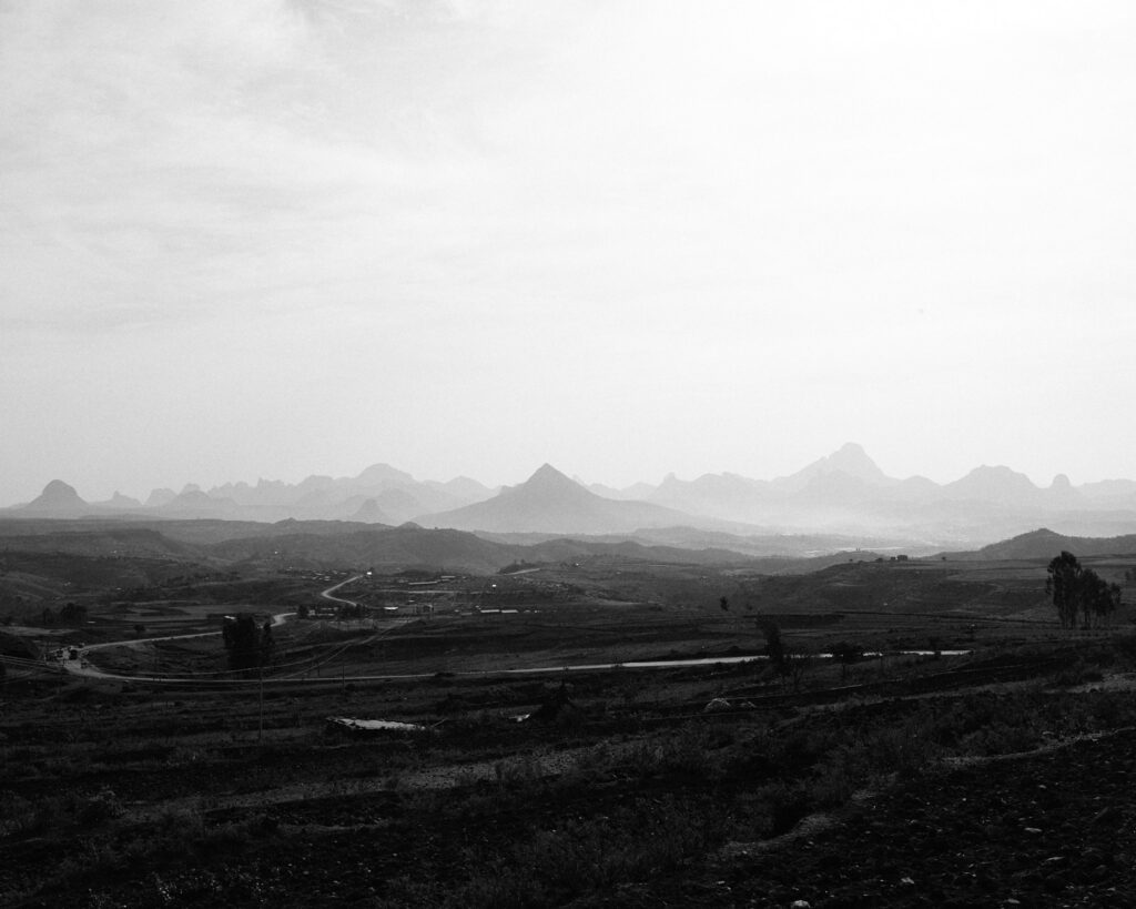 A wide valley of farmland with jagged mountains on the horizon