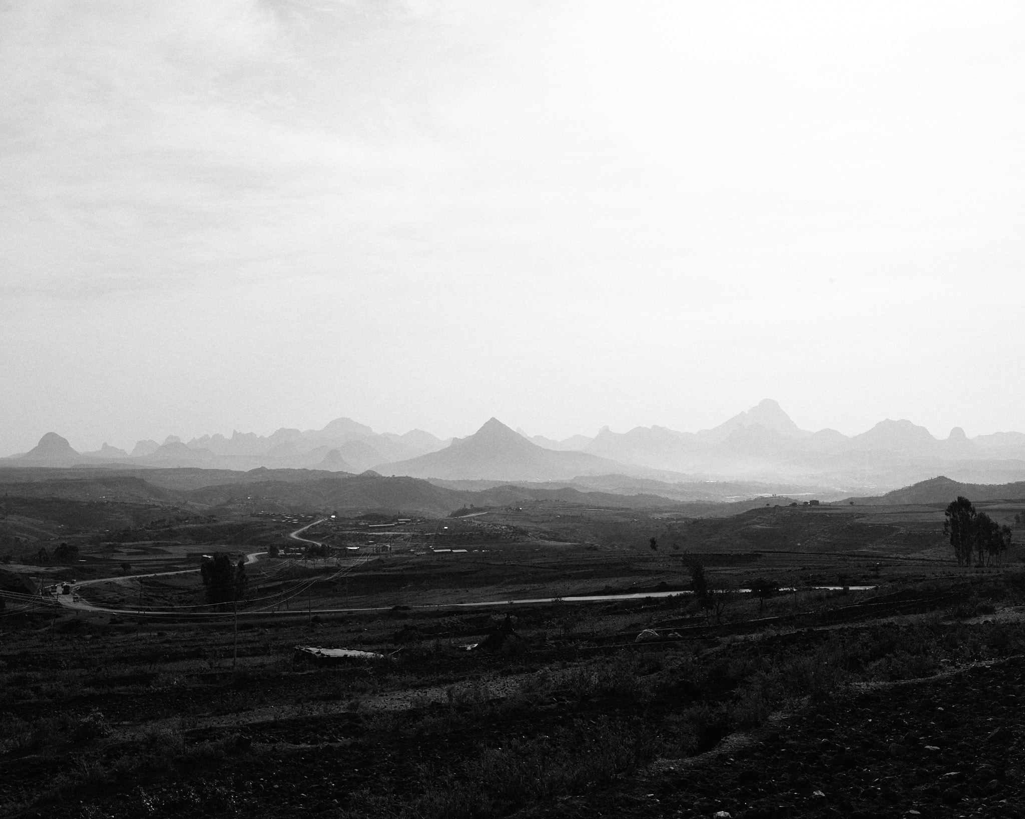 A wide valley of farmland with jagged mountains on the horizon