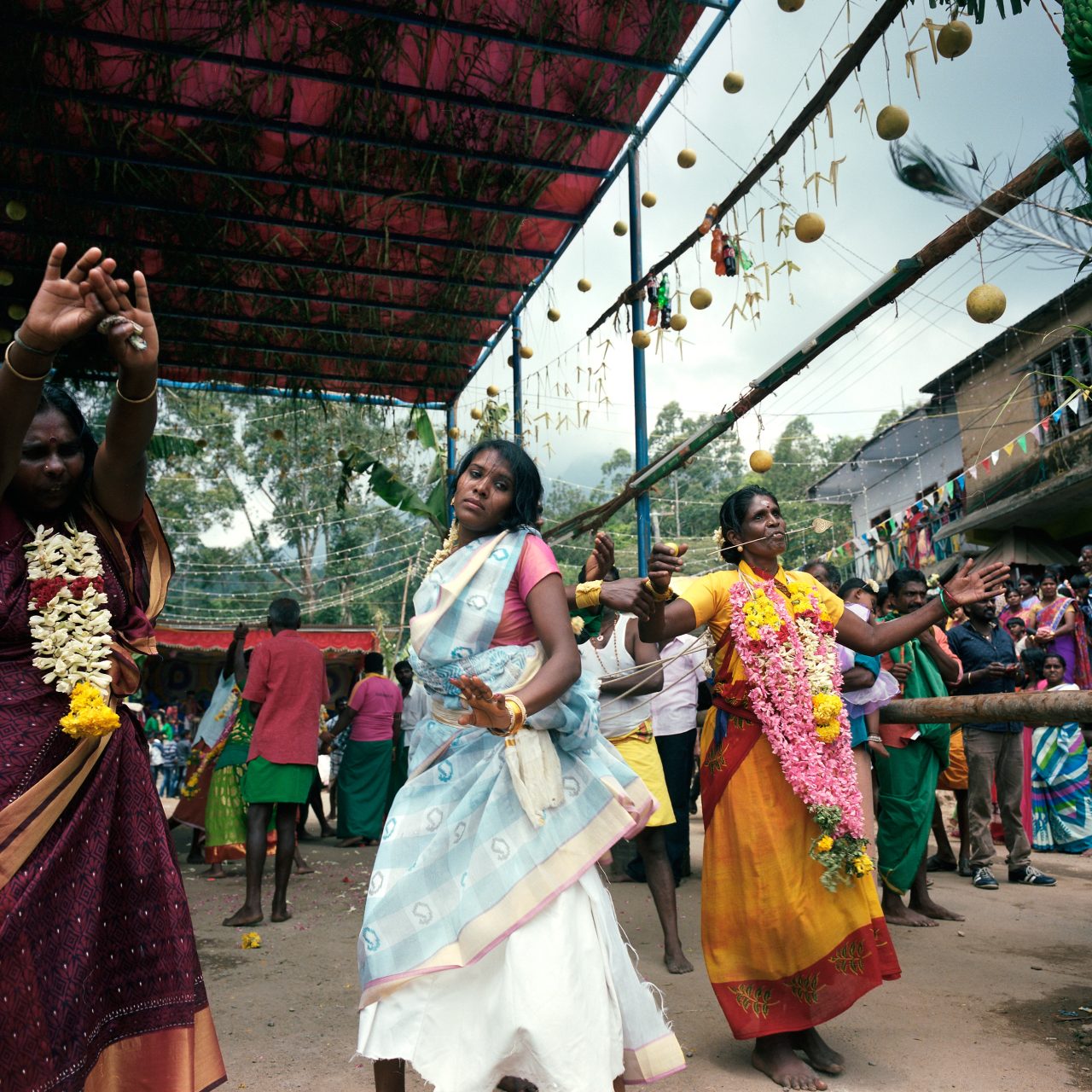 Women in bright saris dancing beneath strings of hanging decorations
